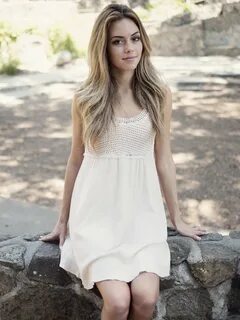 Woman wearing white sleeveless shirt sitting in grey concret