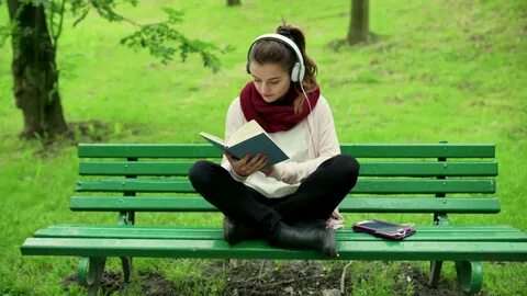 Girl listening music and reading book in the park Stock Vide