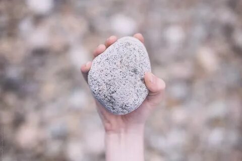 A Hand Holding A Stone Above A Lot Of Stones by Jonas Räflin