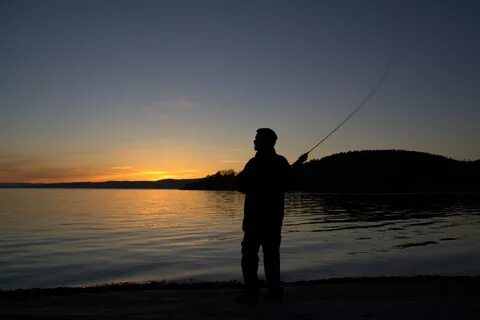 Silhouette of the person Fishing at colorful sunset backgrou