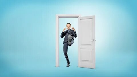 A young businessman stands in a small cut out doorframe and 
