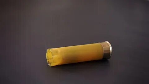 Video Stok spent yellow shotgun shell falls smokes (100% Tan