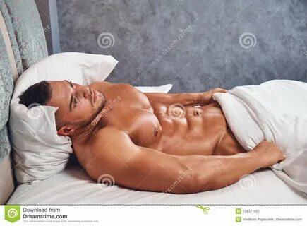 Photo about A naked sporty man relaxing while lying in bed. 