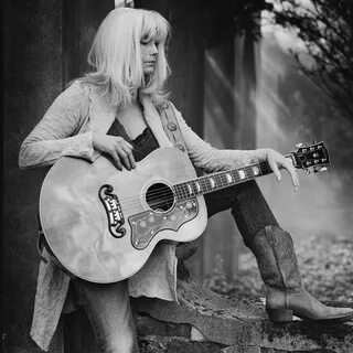 black and white photo of emmylou harris with her guitar in 2