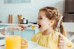 selective focus of mother feeding daughter with pancakes