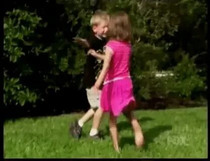 Brunette Girl In Pink Skirt Kicks Blond Boy In The Balls GIF