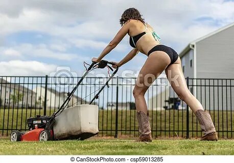 A gorgeous bikini clad model mowing the lawn. A gorgeous bru