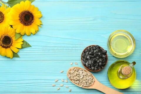 Sunflower Oil, Seeds and Flower on Blue Wooden Background. T