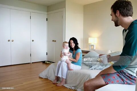 Father Looking At Mother With Baby Girl In Bedroom High-Res 