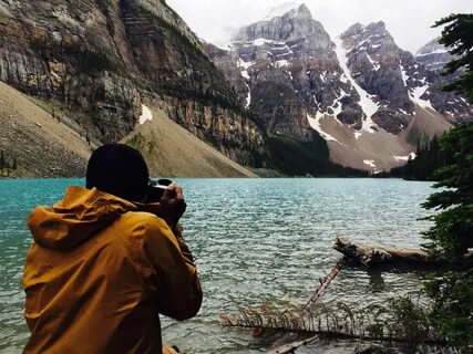 man taking photo of calm lake near mountain view photo - Fre