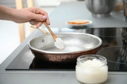 Woman Putting Coconut Oil on Frying Pan in Kitchen Stock Pho