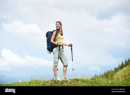 Beautiful happy woman hiker hiking mountain trail, walking on grassy hill, ...