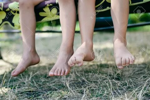Outdoor Picture Of Two Children Legs Barefoot. Closeup Of Ha