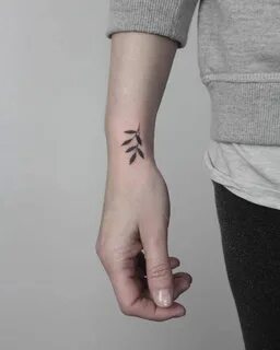 Small black greenery tattoo on the right wrist by Lara M J S