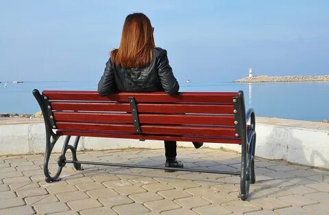 Woman on bench looking at sea, back view free image download