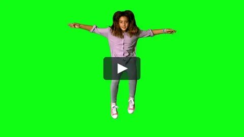 Happy little girl jumping up and down on green screen in slo