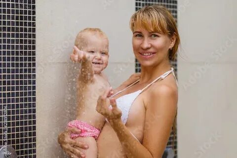 Mom with a daughter in the shower in a swimsuit in the open 