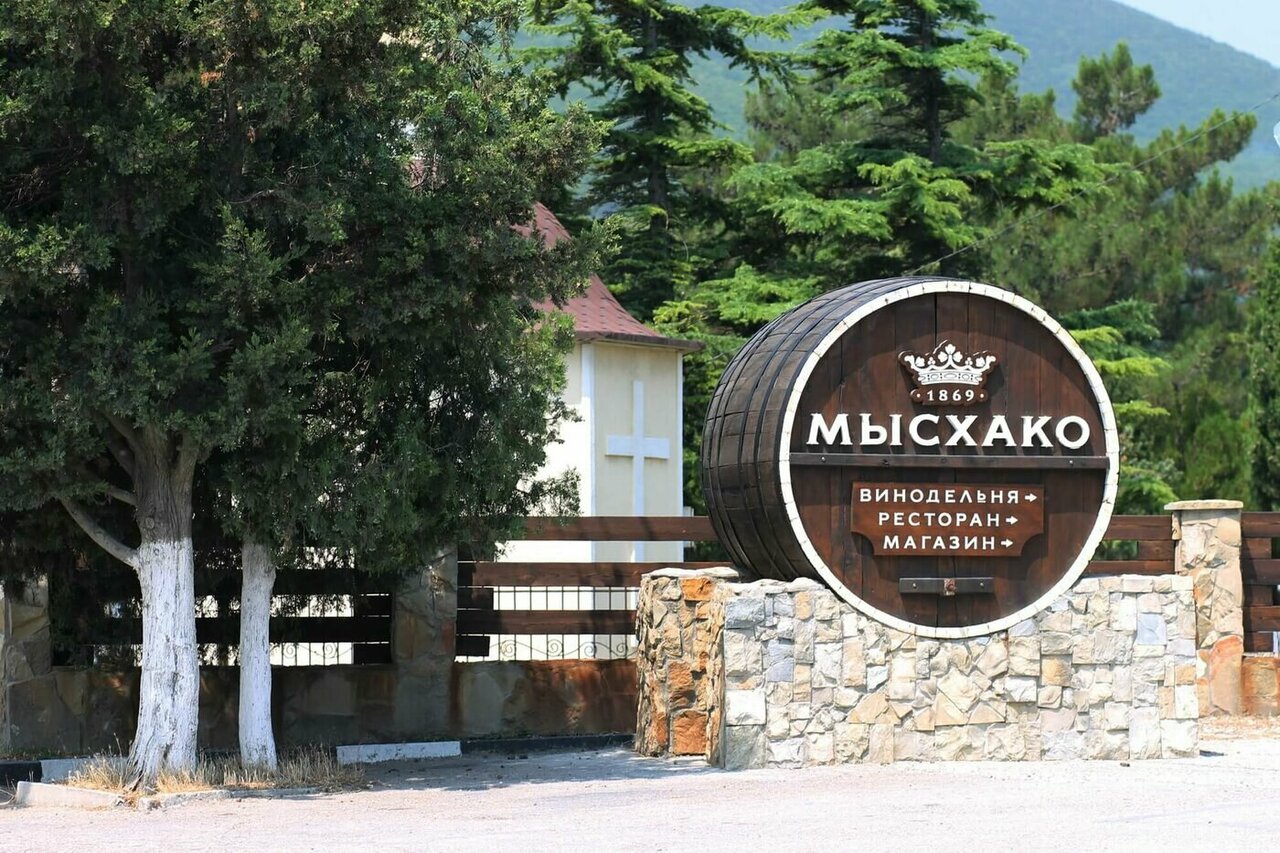 Современное здание винодельни Мысхако на фоне холмов и виноградников.