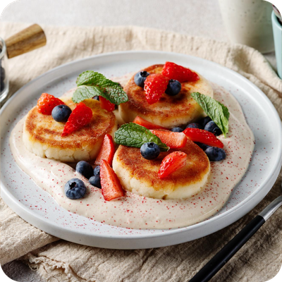 тарелка с готовыми сырниками и ягодами