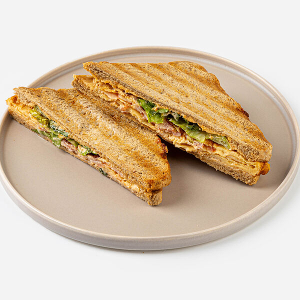 Сэндвич с беконом и скрэмблом на хлебе с отрубями