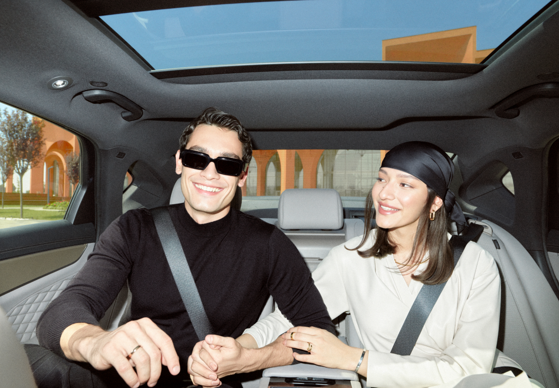 A young couple sitting together in the back seat of a car