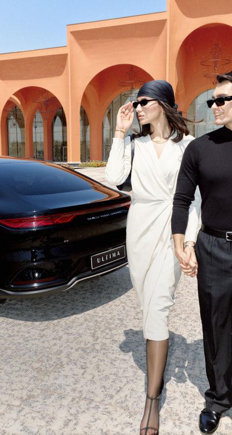 A young man and woman stepping out of a house with a car parked nearby