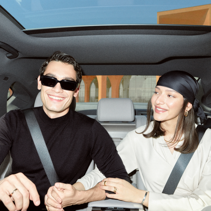 A young couple sitting together in the back seat of a car