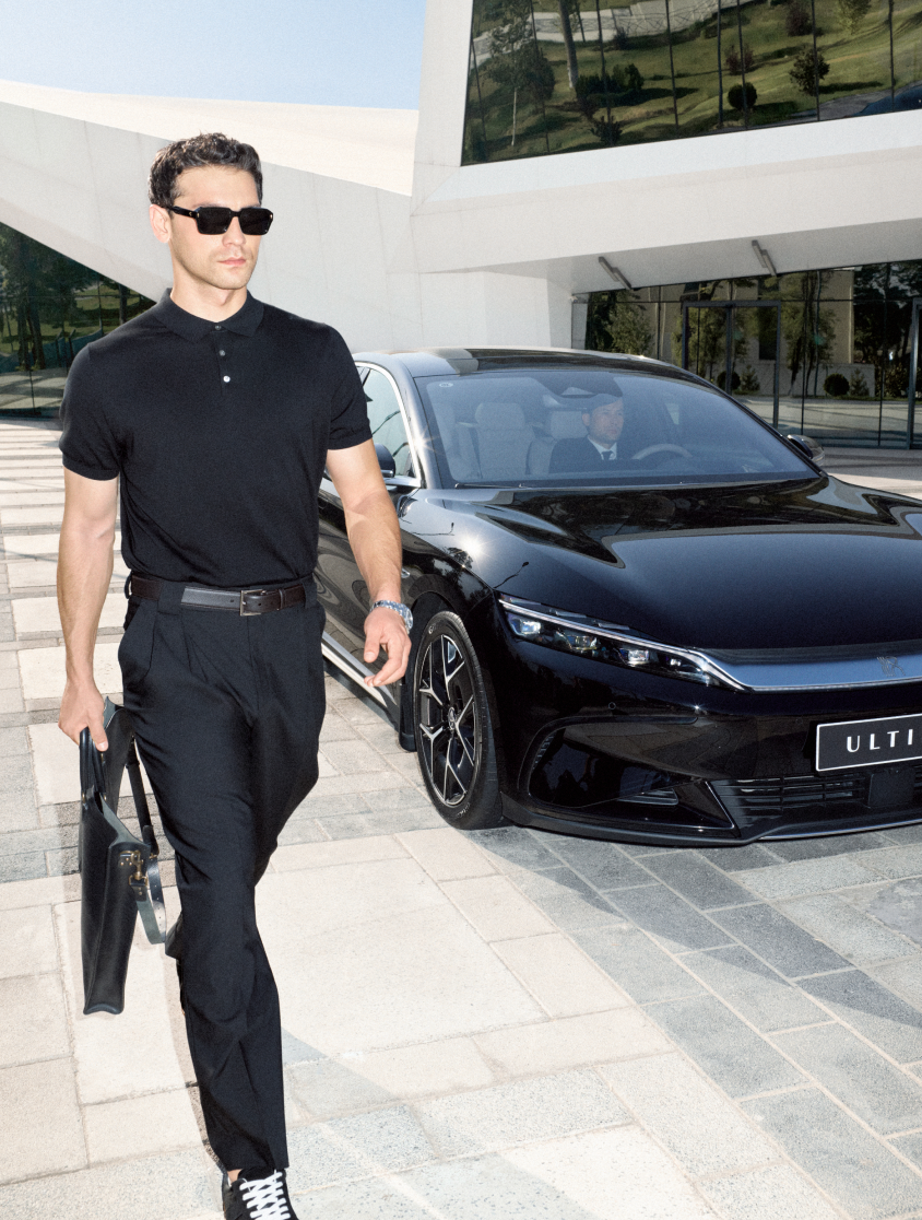 A young man walking away from an expensive car