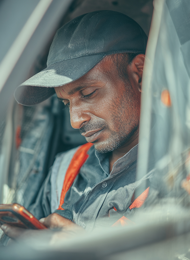 Man in cap using smartphone inside vehicle