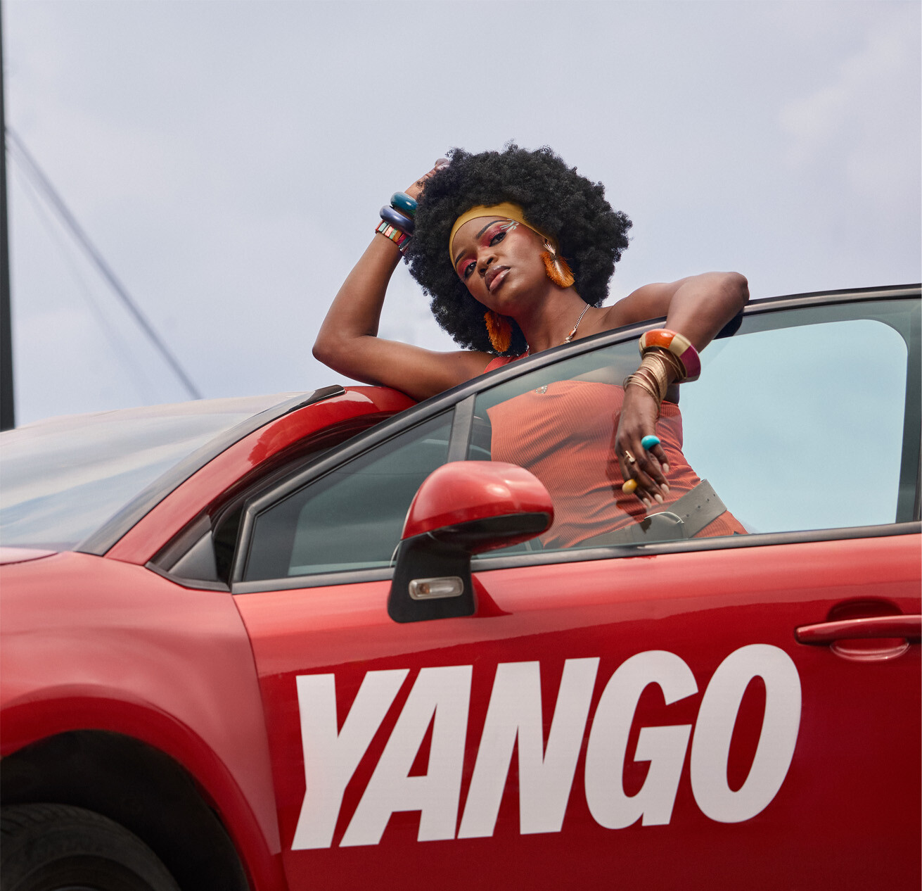 Man in beige jacket leaning on red Vango car