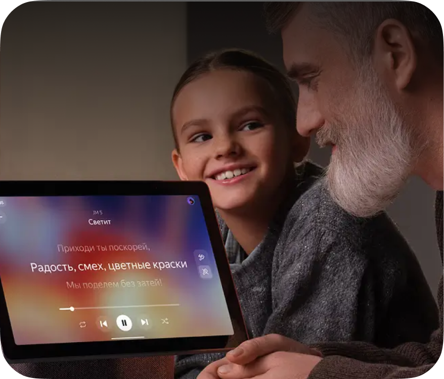 Man and girl smiling, looking at tablet with song lyrics displayed: «Come quickly, Joy, laughter, colorful paints, We'll share without tricks!»