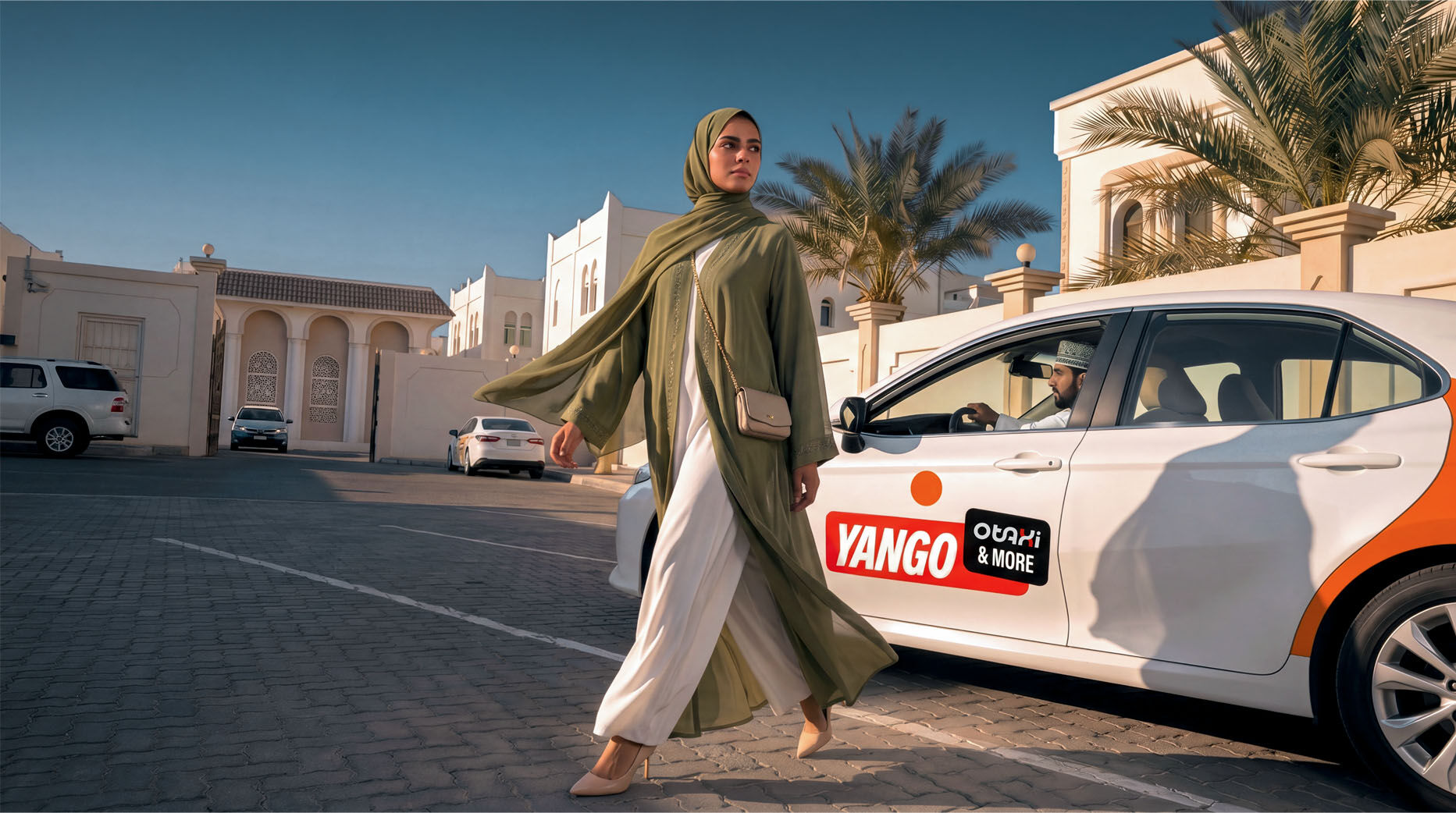 Woman in green abaya and white outfit walking past white car with YANGO & MORE logo; man in car wearing cap; palm trees, white buildings, parked cars in background
