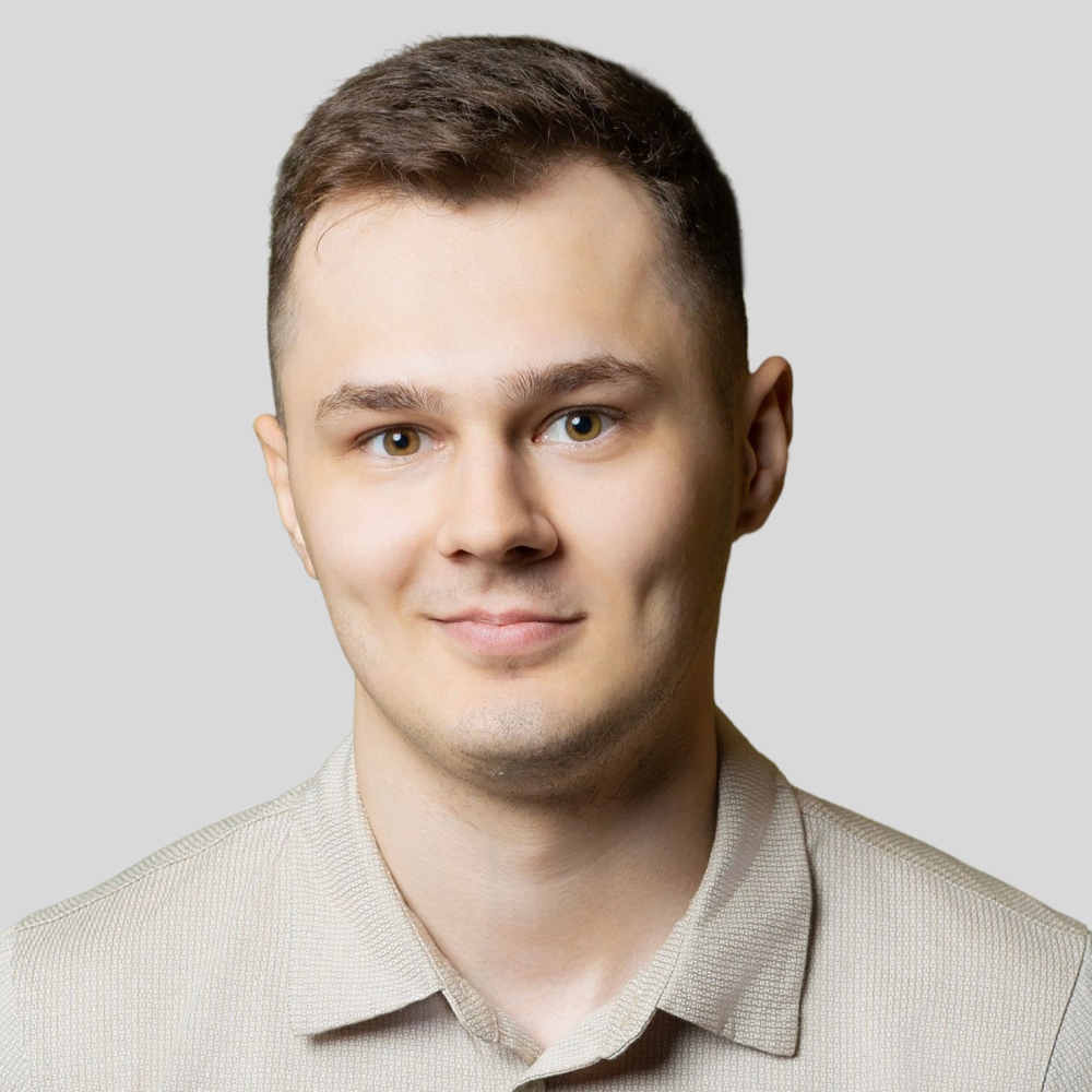 Мужчина с тёмными волосами и бородой, в очках и красном свитере с высоким воротом
