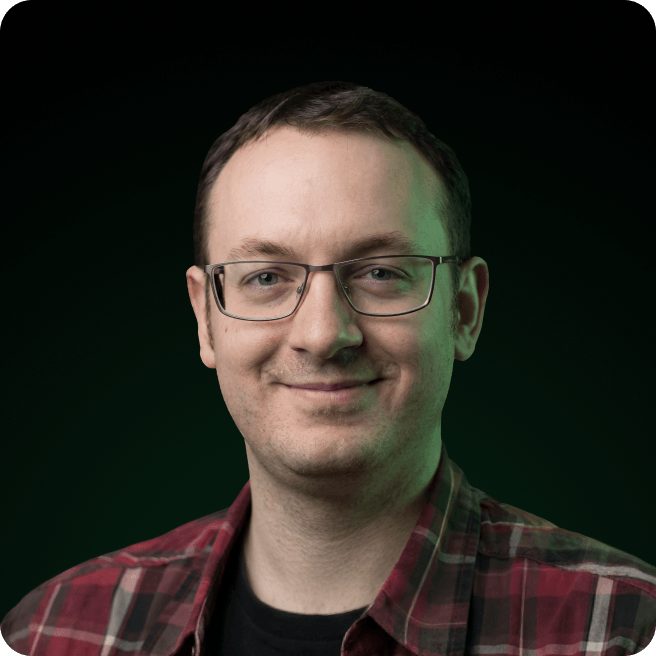 Man with short brown hair, glasses, plaid shirt, slight smile