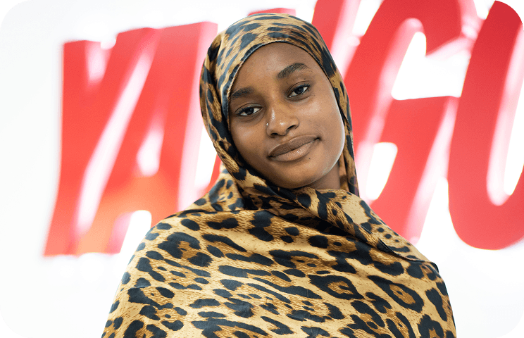 Woman wearing leopard-print hijab, red blurred text in background