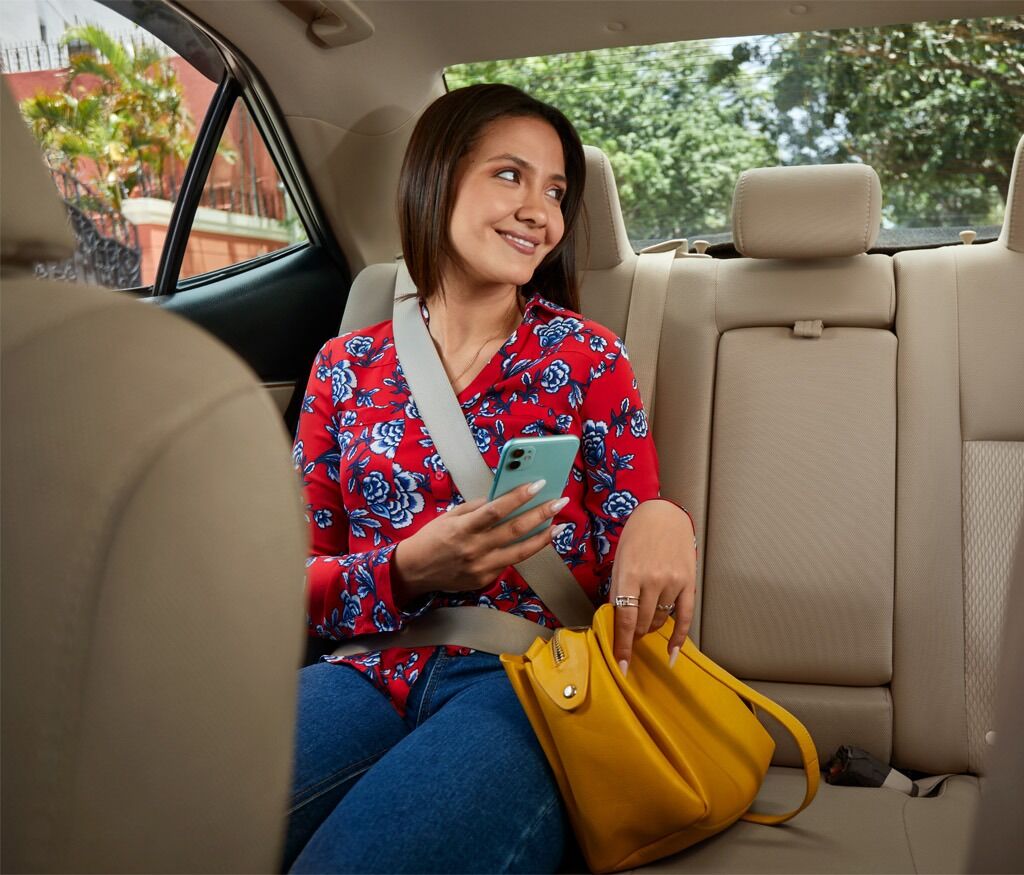 Woman in red floral shirt, holding phone, yellow bag, seatbelt