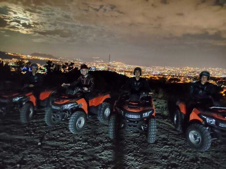 Kurt Atv Safari практикует сафари после заката с видом на ночные огни города.