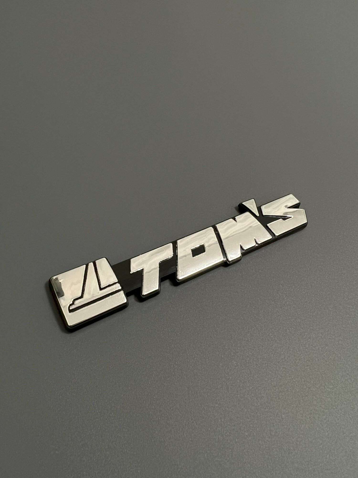 Шильдик TOMS на багажник автомобиля
