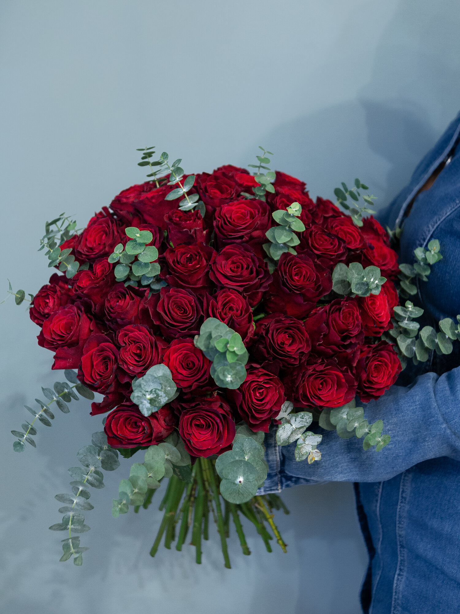Букет живых цветов из 19 роз темно красного цвета с добавлением эвкалипта высотой 50 см