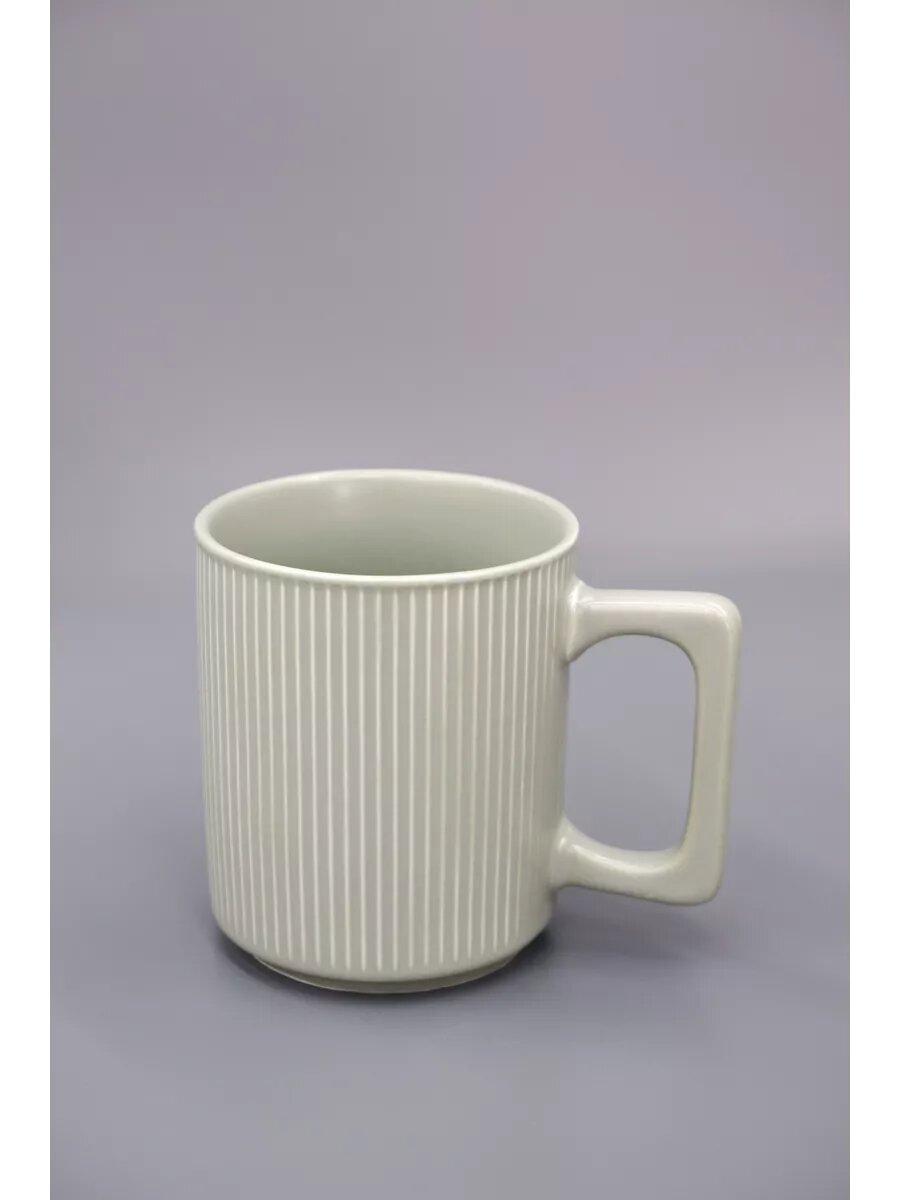 Керамическая кружка с вертикальными ребристыми линиями и квадратной ручкой.