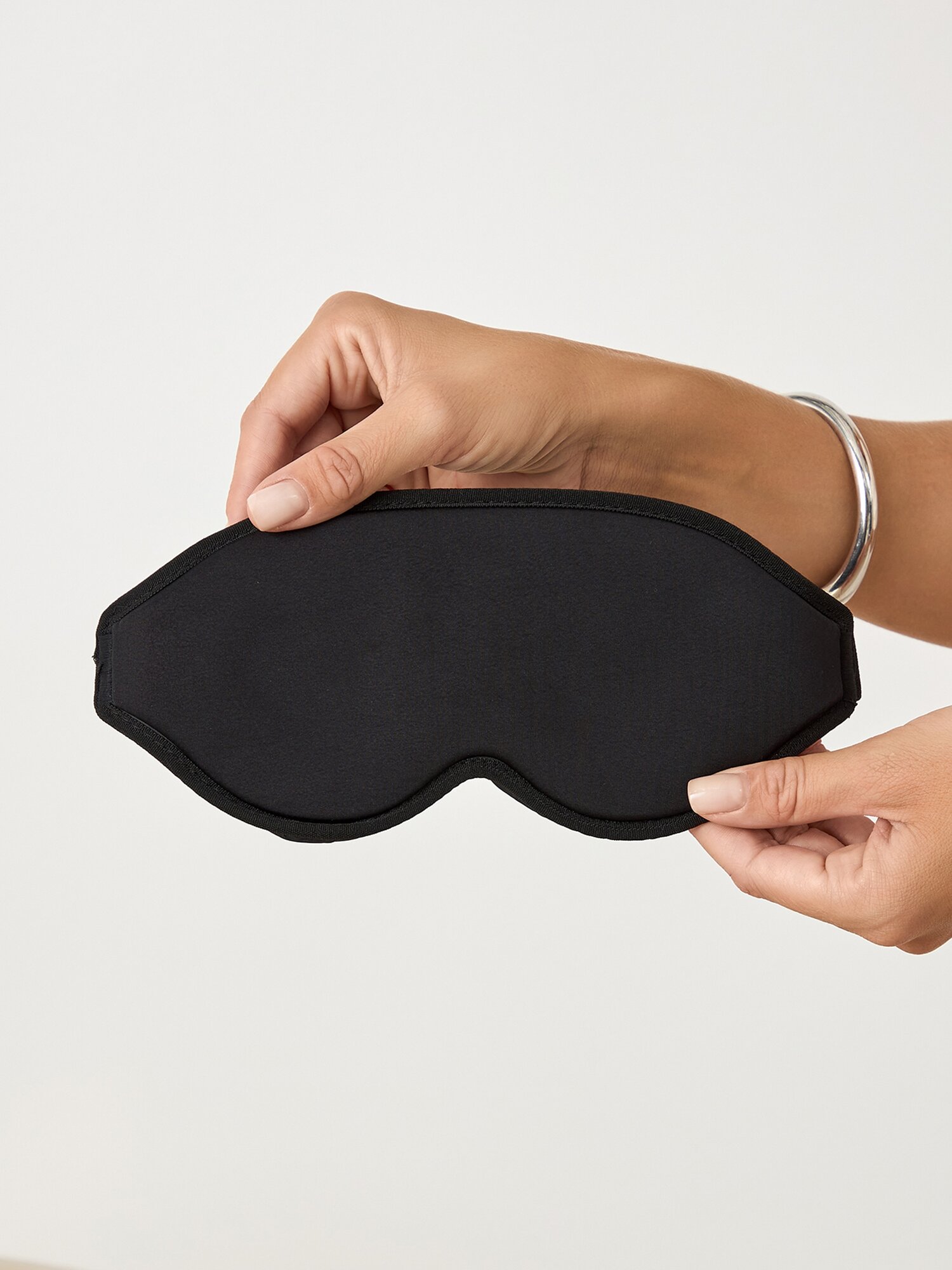 Подарочная коробка с черной матовой маской для сна на фоне интерьера спальни