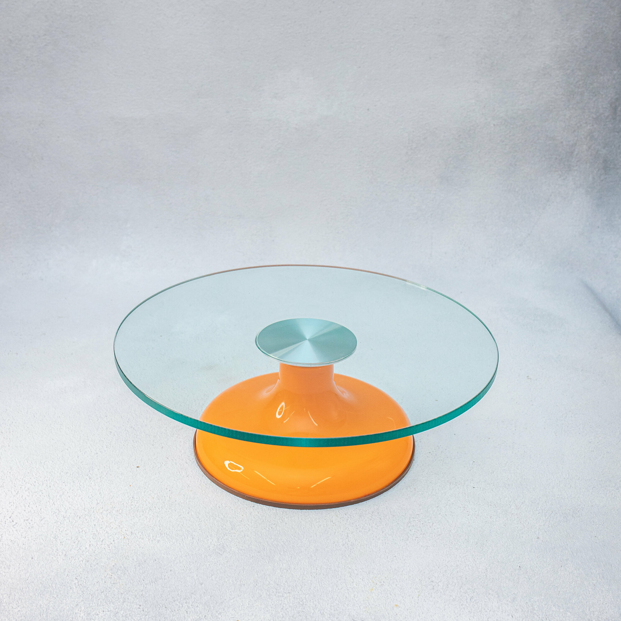 Поворотный столик с оранжевой ножкой и стеклянной поверхностью