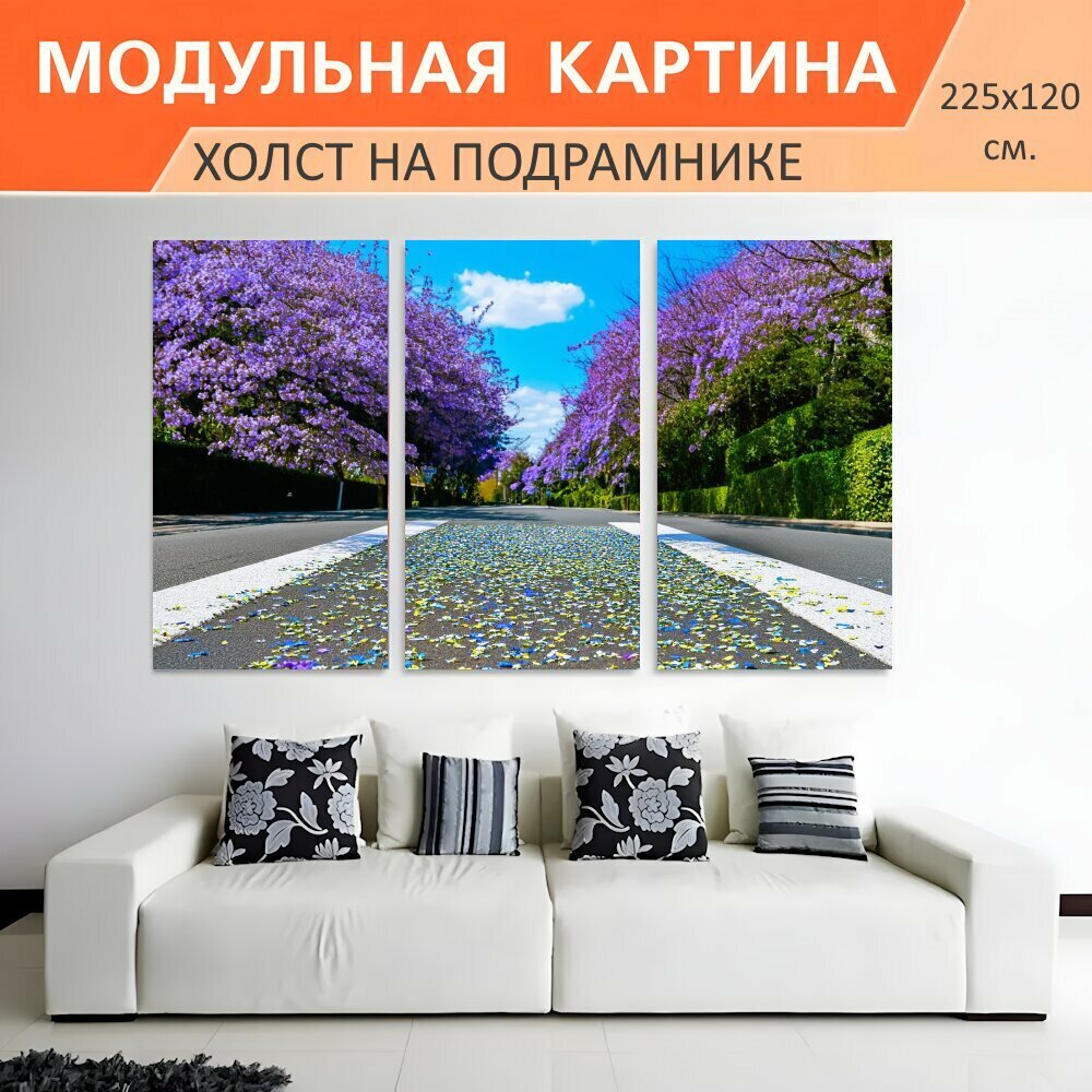 Модульная картина на холсте "Улица, усыпанная цветочными лепестками, с фоном из деревьев с фиолетовыми цветами. Яркое голубое небо и." триптих на подрамнике 225х120 см. для интерьера