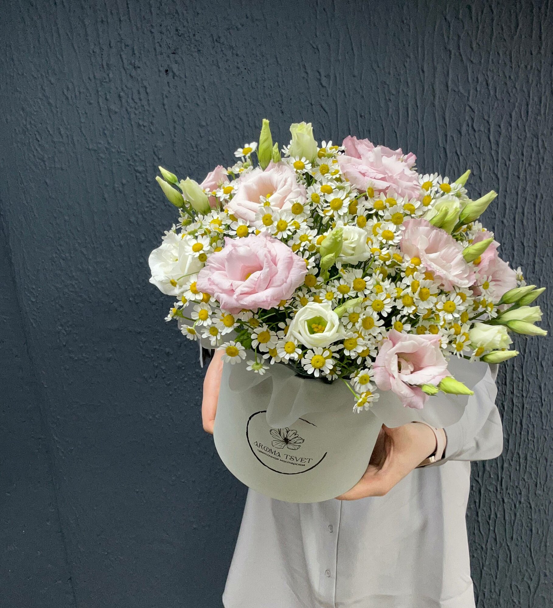 Букет живых цветов в коробке из ромашек и эустомы в дизайнерской упаковке.