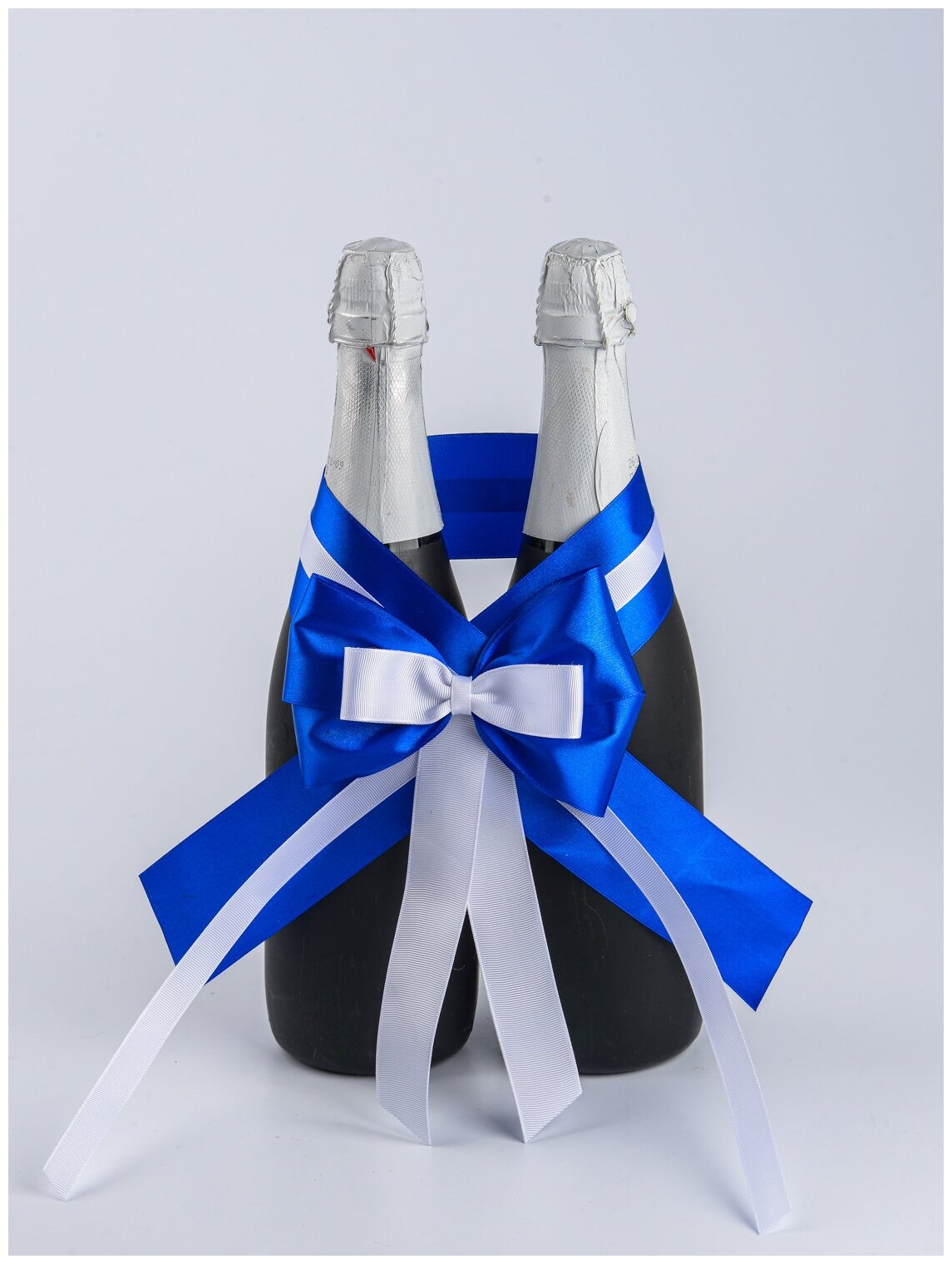 Свадебное украшение для двух бутылок шампанского молодоженов с атласным бантом и лентами в бело-синих тонах