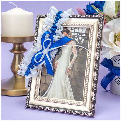 Яркая ажурная подвязка на свадьбу невесте из белого кружева с цветочными узорами и бантом из синей атласной ленты
