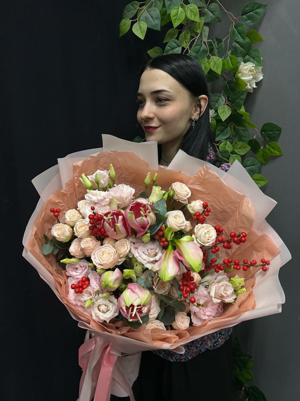 Авторский букет с красным илексом кустовой пионовидной розой и амариллисами в персиковой упаковке