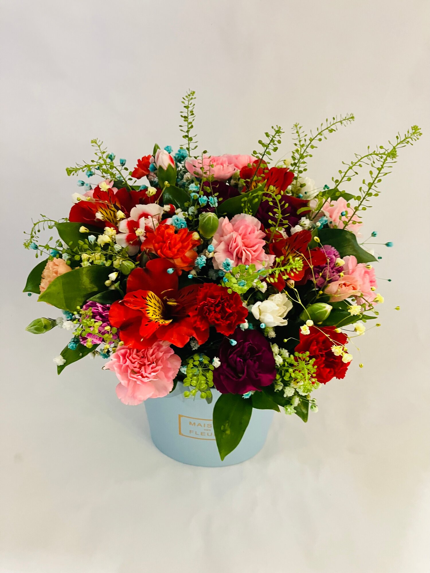 Букет Композиция из кустовых гвоздик гринбелла и красной альстромерии в серо-голубой коробке