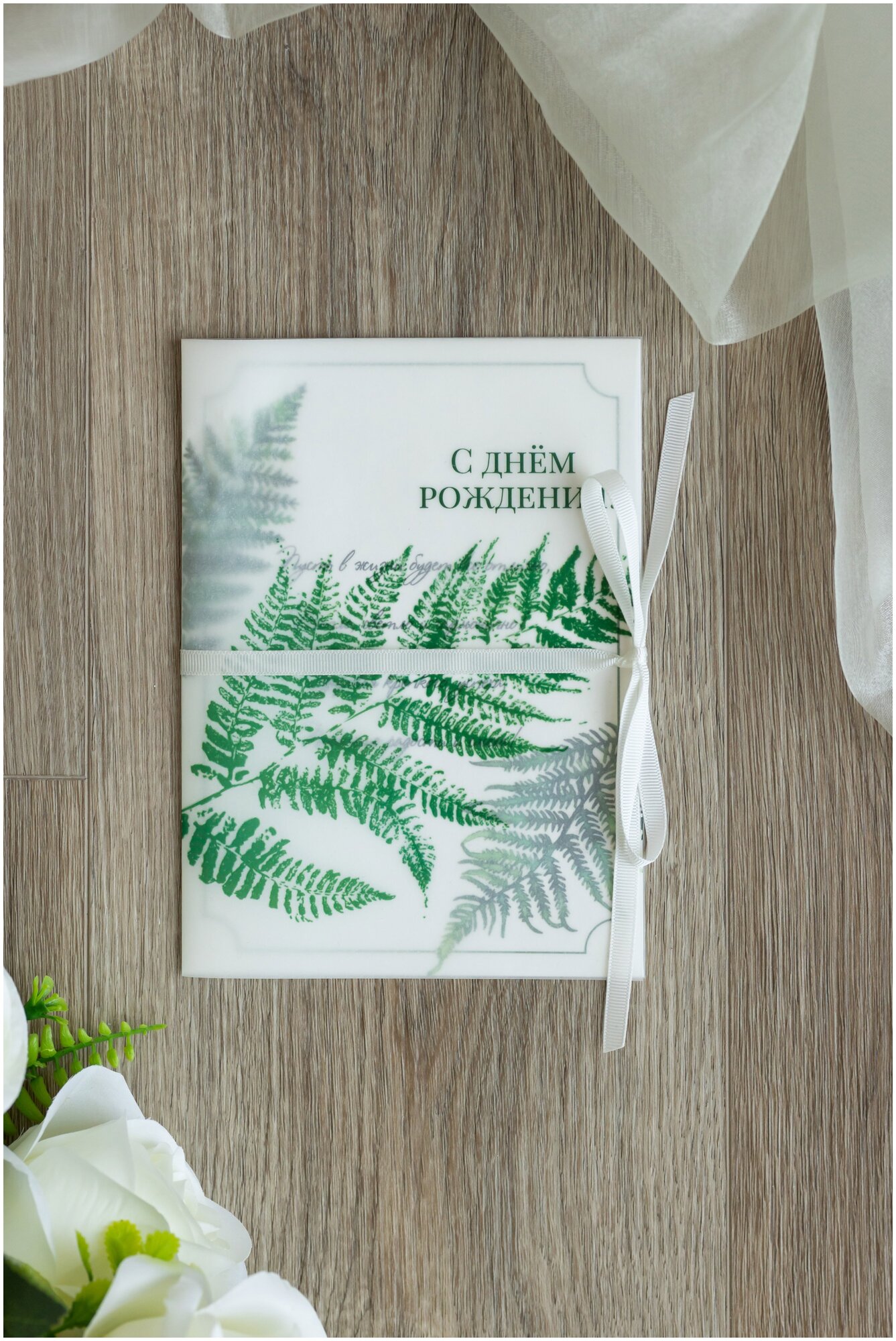Открытка в природном стиле "С днем рождения" с зеленым принтом папоротника и обложкой из кальки, с белой атласной лентой
