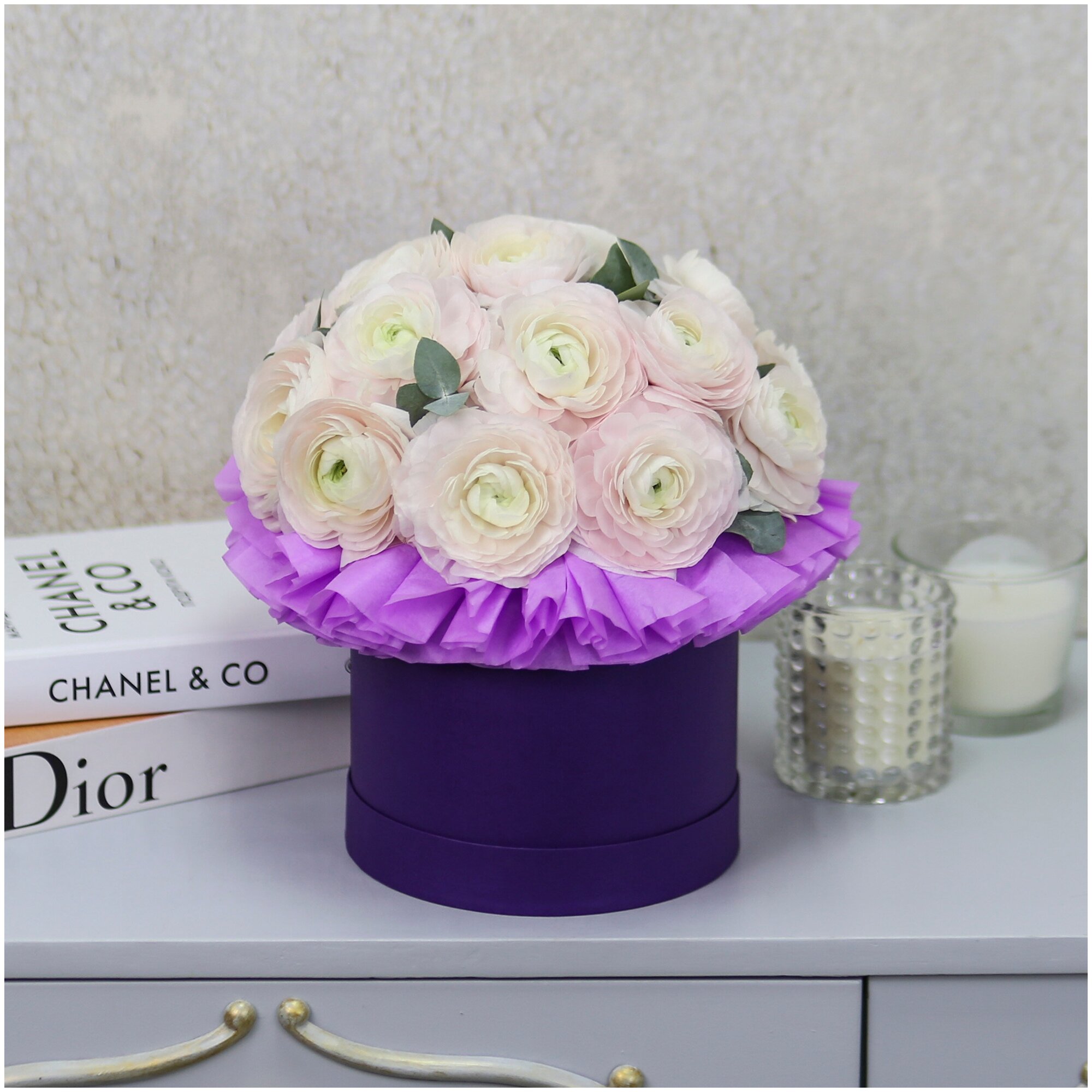 Букет живых цветов из 17 ранункулюсов в фиолетовой шляпной коробке